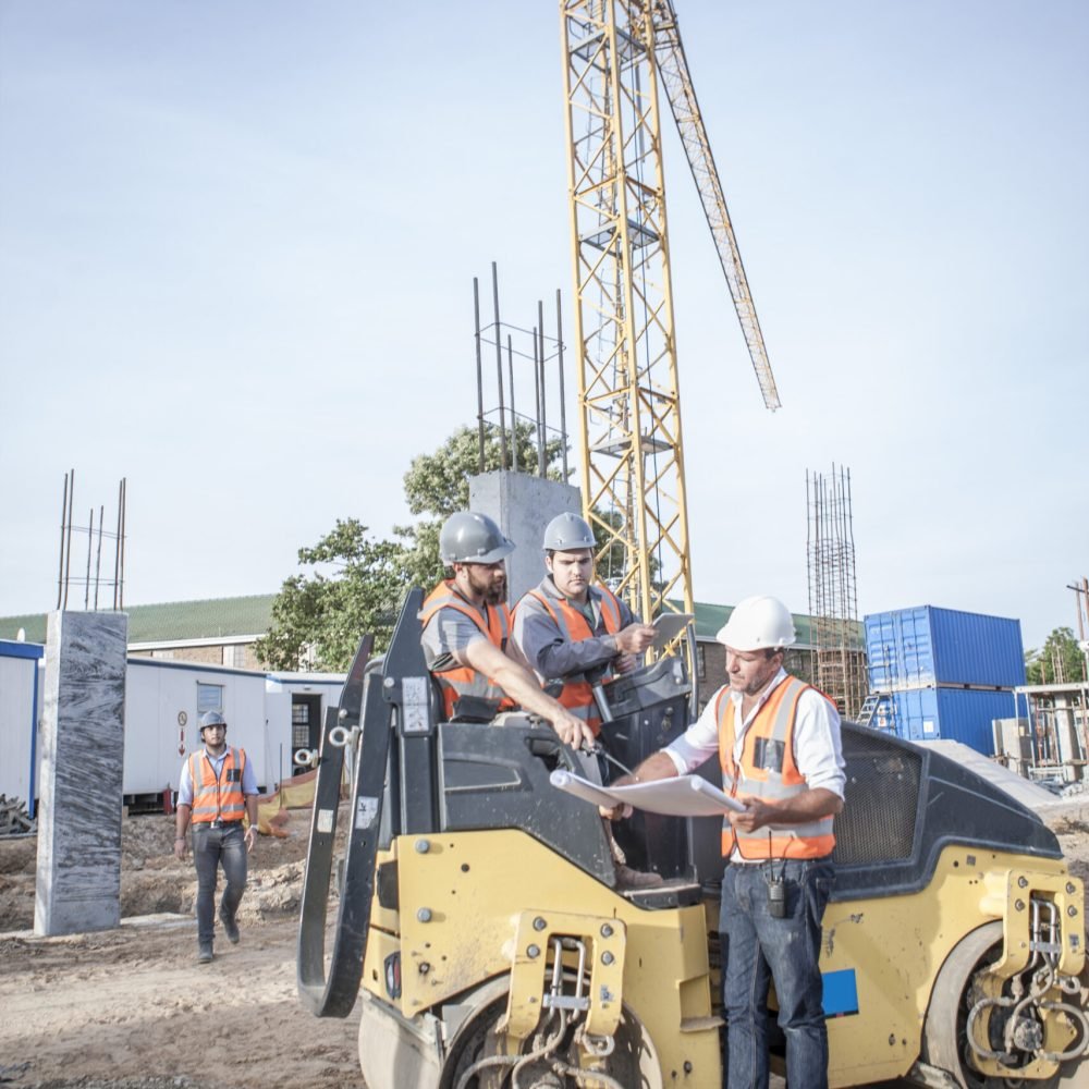 Site manager talking with drivers about blueprint on construction site
